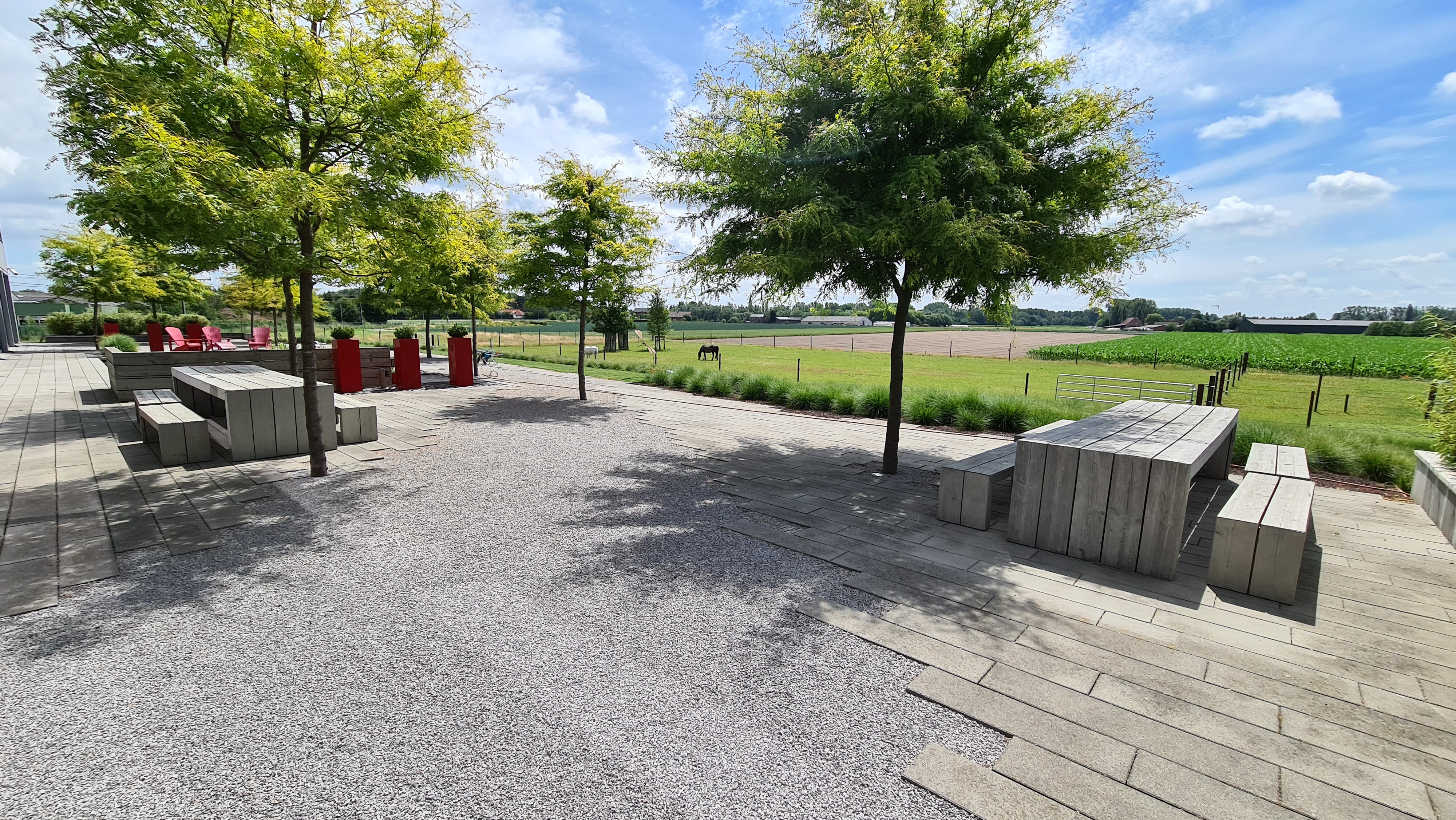 Groot terras met tafels tussen de bomen naast het gebouw